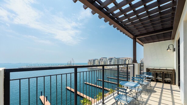 A balcony with a view of the sea, a pergola, and outdoor seating. - Maison Privee - Stunning Waterfront Apt w/ Open Sea Vws in La Mer (Dubai)