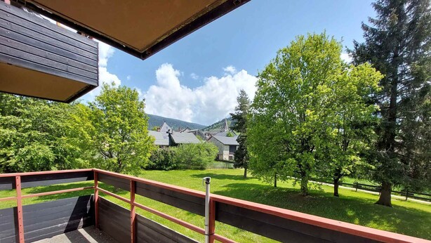 A balcony with a view of a green lawn, trees, and houses in the background. - Apartment 6 ppl, south balcony, near cross-country ski slopes (Autrans-Méaudre en Vercors-Autrans)