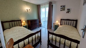 A room with two beds, a wooden chair, a dresser, and a window with curtains. - Apartment 6 ppl, south balcony, near cross-country ski slopes (Autrans-Méaudre en Vercors-Autrans)