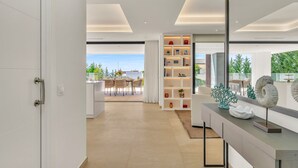 A modern interior with a dining area, a bookshelf, and a large mirror. - Villa Alejandra (Benahavís)