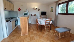A compact kitchen with wooden cabinets, a microwave, a sink, and a dining area with a table and chairs. - Beautiful duplex for 6, slopeside with parking (Autrans-Méaudre en Vercors-Autrans)