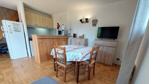 A compact kitchen with wooden cabinets, a microwave, a refrigerator, a dining table with chairs, and a television. - Beautiful duplex for 6, slopeside with parking (Autrans-Méaudre en Vercors-Autrans)