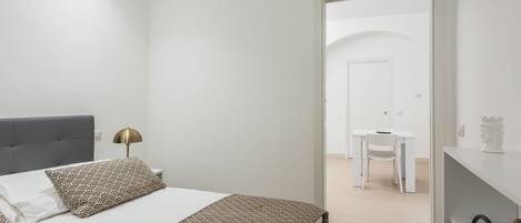 Une chambre à coucher moderne, avec un lit, une table de chevet, une lampe et une vue sur l’espace repas.