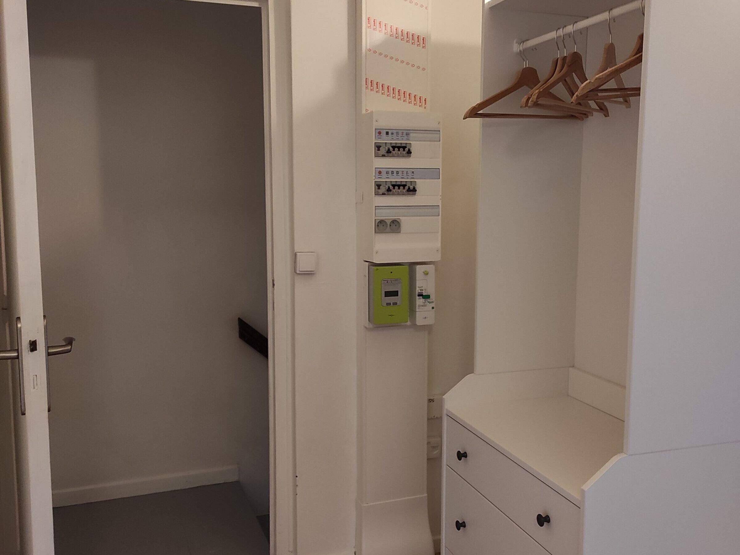 Un placard blanc avec des cintres en bois et une commode blanche.