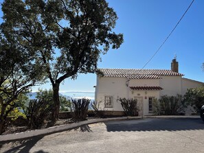 A single-story building with a tiled roof, a stone chimney, and a white exterior. - Villa Panoramique sur Baie de Roses Cap Creus (El Mas Fumats)