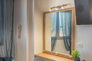 Bathroom features a large mirror, a small plant, and a wall-mounted light fixture.
