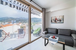 Relax on the balcony with a sofa, table, and chair, taking in the view through the large sliding glass door.