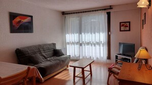 A living room with a sofa, a TV, a table, and a lamp.