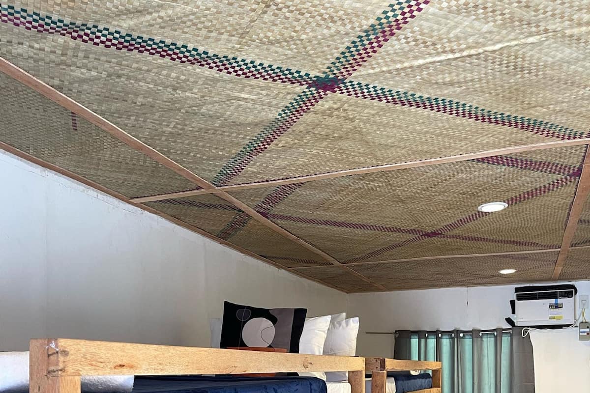 Una habitación con literas, un techo con diseño geométrico y una pequeña mesa con un altavoz.