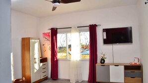 A bedroom with a bed, a wardrobe, a desk with a TV, and a window with curtains. - Room-the Romantic Atmosphere of the red (Antananarivo)