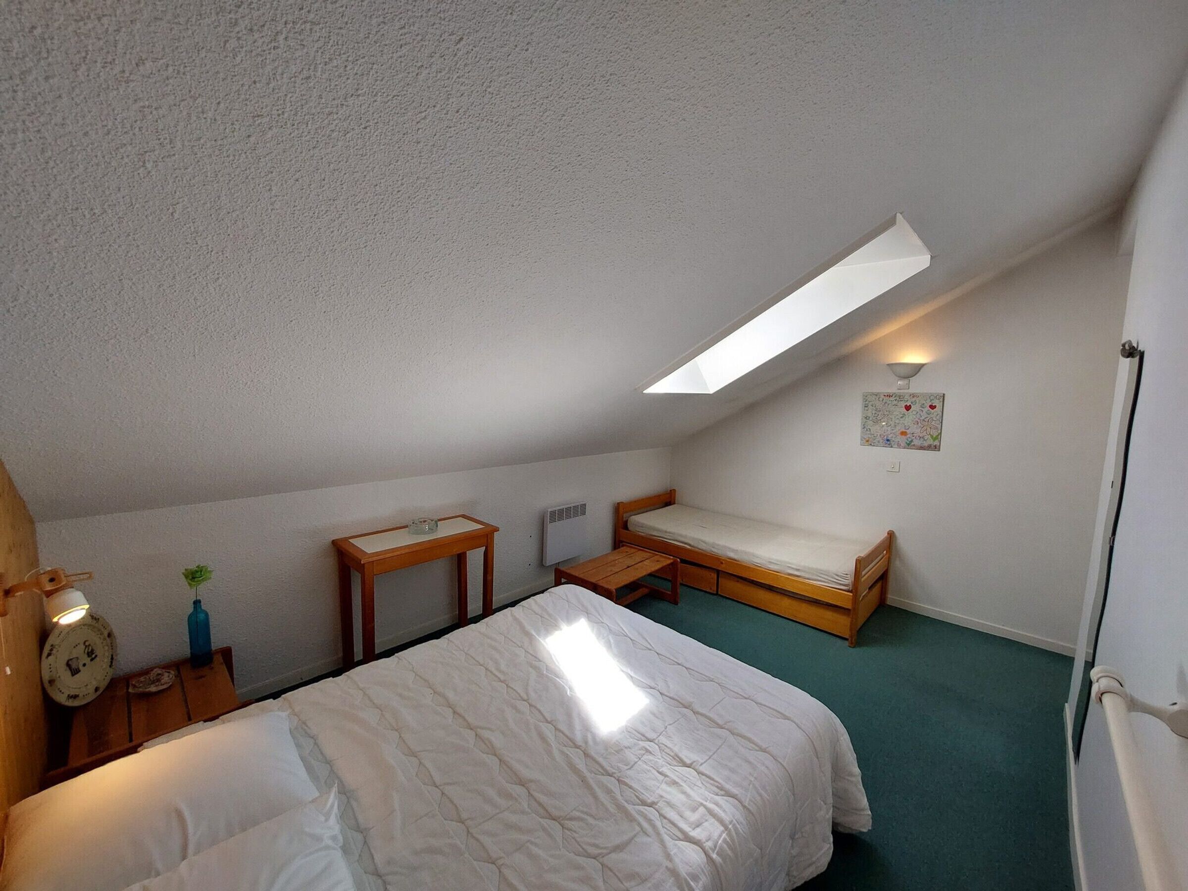 A small, simple room with a bed, a table, and a bench.