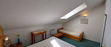 A small, simple room with a bed, a table, and a bench.