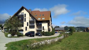 A multi-story building with a sloped roof, several balconies, and a paved driveway. - Renovated apartment with balcony, parking and wifi, close to slopes - Méaudre (Méaudre)