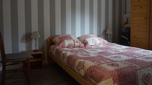A bedroom with a wooden bed, striped wallpaper, a wooden wardrobe, and a chair. - Apartment in Méaudre - 4 pers, near center, balcony, parking (Méaudre)