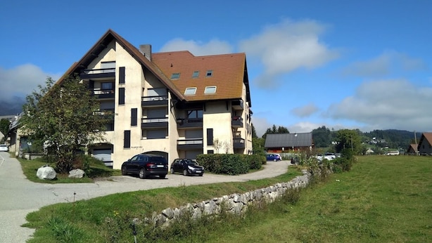 A multi-story building with a sloped roof, several balconies, and a paved driveway. - Apartment in Méaudre - 4 pers, near center, balcony, parking (Méaudre)