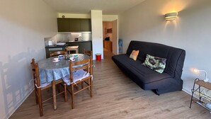 Un espacio habitable compacto con comedor, un sofá negro y una kitchenette.