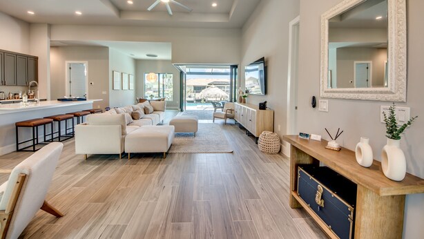 A spacious living area with a modern kitchen, a large mirror, and a view to the outdoors. - Villa Escape - brand new, with pool and spa, on water with gulf access (Cape Coral)