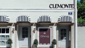 A building with the name 'CLEMONTES' on the facade, a parked convertible car, and a street sign indicating the number 25.
