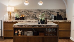 A kitchen with marble countertops, wooden cabinets, and pendant lighting.