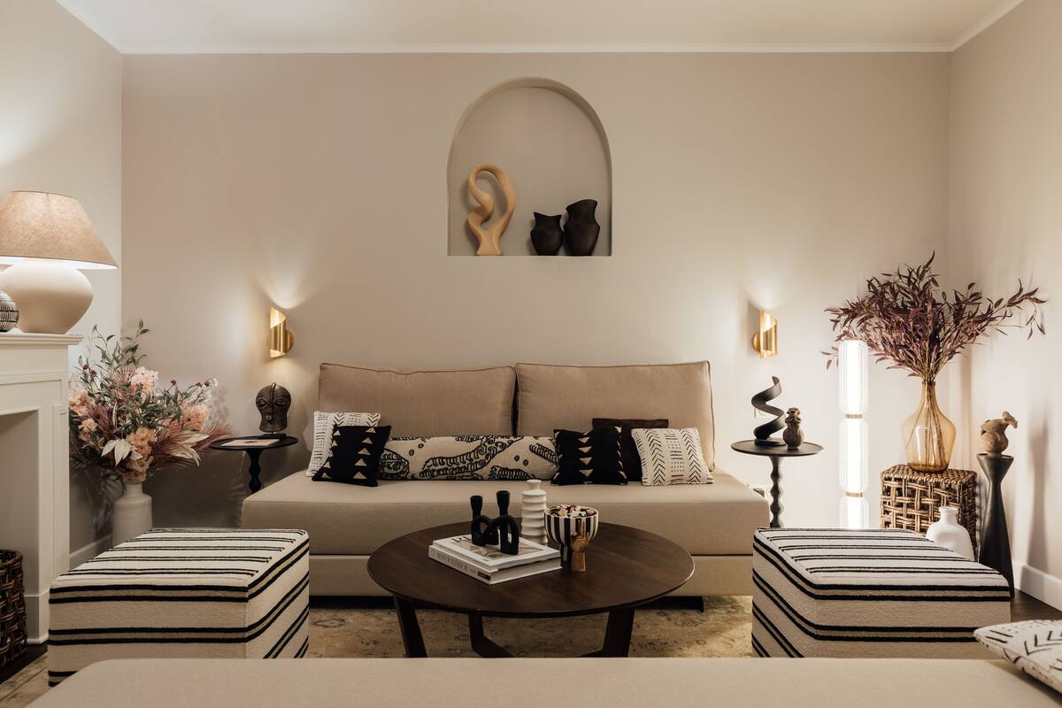 Een moderne woonkamer met een bank, poefjes, een salontafel en decoratieve objecten.