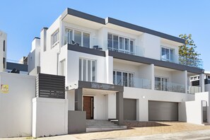 A modern two-story residential building with a flat roof, large windows, and a balcony. - Endless Summer Beach House (Cape Town)