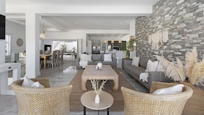 A spacious living area with a stone wall, a central coffee table, and wicker furniture. - Endless Summer Beach House (Cape Town)