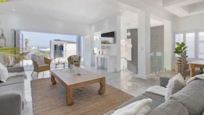 A spacious living area with a sofa, coffee table, and a view of the outdoors. - Endless Summer Beach House (Cape Town)