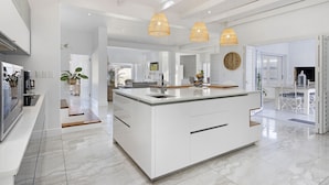 A modern kitchen with a central island, white cabinetry, and pendant lighting. - Endless Summer Beach House (Cape Town)