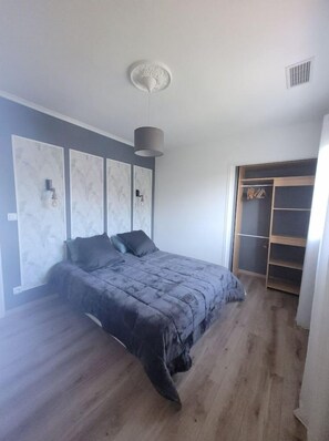 Un dormitorio con cama, armario y lámpara en el techo.