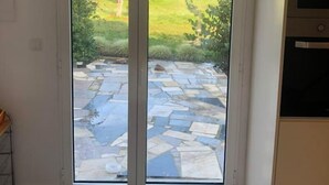 A kitchen with a large sliding glass door leading to a stone patio. - Maison 5 Chambres, Piscine Partagée-plage à 2.5 km (Luz)