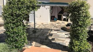 A courtyard with a tiled patio, a pergola, and a building with a tiled roof. - Maison 5 Chambres, Piscine Partagée-plage à 2.5 km (Luz)