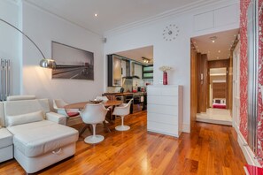 A modern living room with a dining area, a kitchen, and a bedroom.