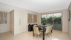 A modern dining area with a large table, chairs, and a view through a glass door to the outdoors.