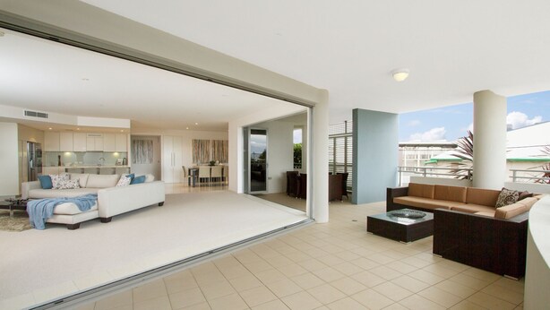 A spacious living area with a sofa, coffee table, and a dining area with chairs and a table.