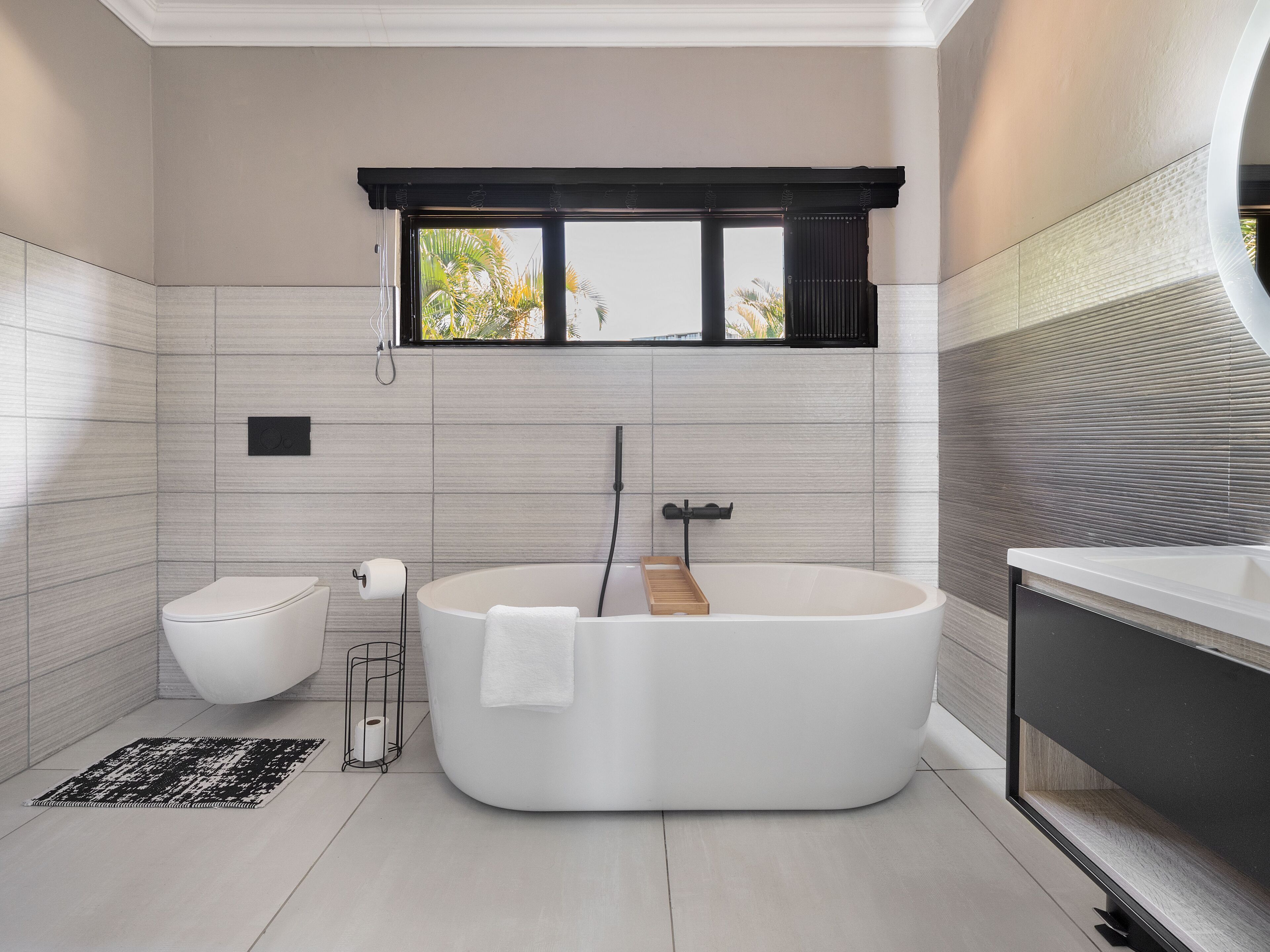 Un baño moderno con una bañera independiente, inodoro y tocador.