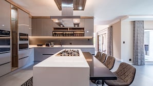 A modern kitchen with a central island, built-in appliances, and a dining area with bar stools. - One on Chelsea (Umhlanga)