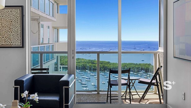 A spacious balcony with a clear view of the sea and boats, a black leather sofa, and a small table with chairs. - 1-BD Condo in Coconut Grove | Water Views (Miami)