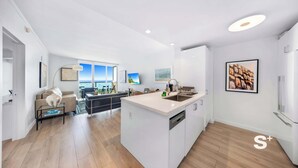 A modern kitchen with a large island, white cabinetry, and a view to the living area. - 1-BD Condo in Coconut Grove | Water Views (Miami)