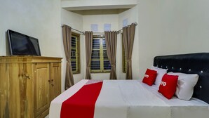 A neatly arranged bedroom with a bed, a wooden wardrobe, and a television on a stand. - Hotel O My Guest House Syariah (Padalarang)