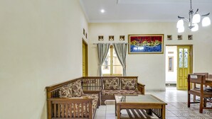 A spacious living room with a wooden sofa set, a coffee table, and a dining table. - Hotel O My Guest House Syariah (Padalarang)