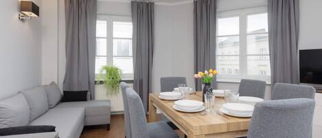Relax in this stylish living area with a dining table for four, a comfortable sofa, and a flat-screen TV.