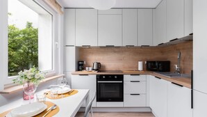 Una cocina moderna con armarios blancos, encimera de madera y horno empotrado.