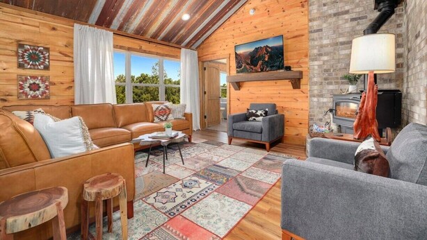 Un salon chaleureux avec des murs en bois, une cheminée et une grande fenêtre.