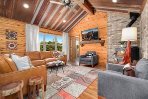 Una sala de estar acogedora con paredes de madera, una chimenea y un ventanal grande.