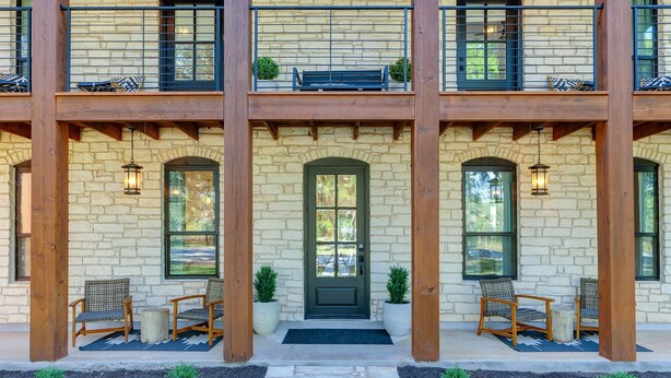 A two-story building with a stone facade, wooden balcony railings, and a green door. - Three Dog Ranch - Pool, Game Room & Sleeps 18 (Driftwood)
