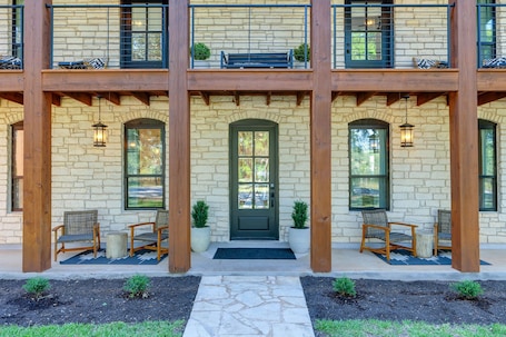 A two-story building with a stone facade, wooden balconies, and a front door with a green mat.. Three Dog Ranch - Pool, Game Room & Sleeps 18