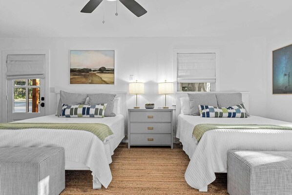 A bedroom with two beds, a nightstand, a ceiling fan, and a painting on the wall. - Three Dog Ranch - Pool, Game Room & Sleeps 18 (Driftwood)