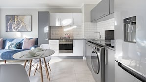Una cocina moderna con armarios blancos, horno empotrado, lavadora y dispensador de agua.