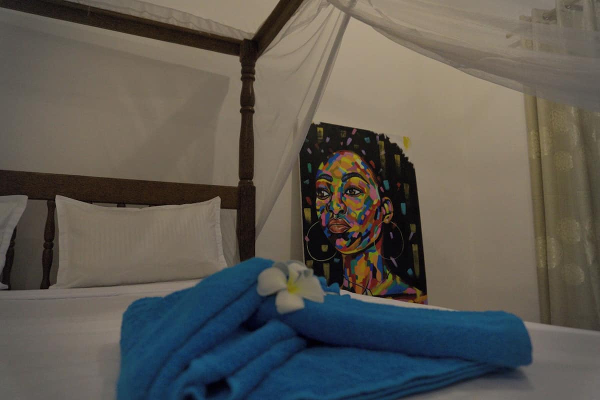 A bed with a white canopy and a colorful painting on the wall.