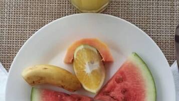 Un plato de frutas cortadas y un vaso de jugo de naranja sobre una mesa.